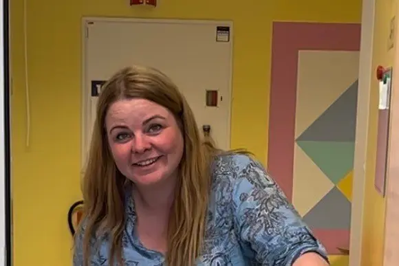 En kvinne som smiler og holder en pose